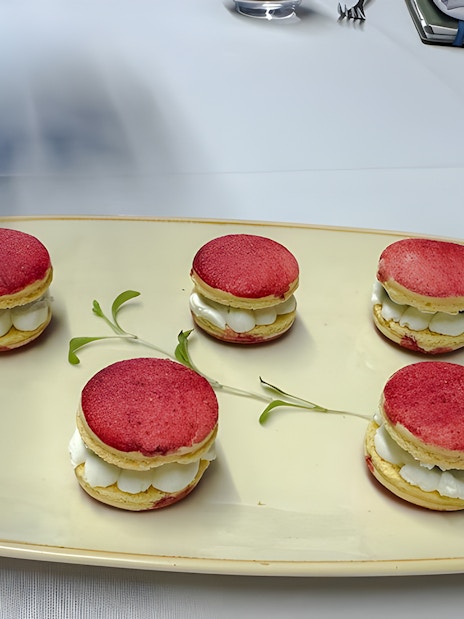 Small red macarons with white cream filling on a plate.