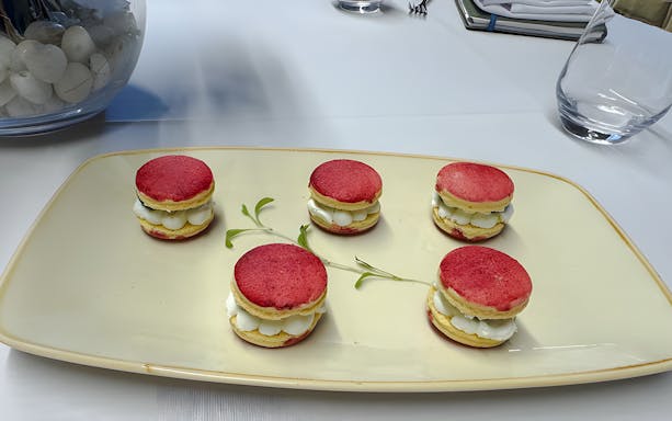 Small red macarons with white cream filling on a plate.