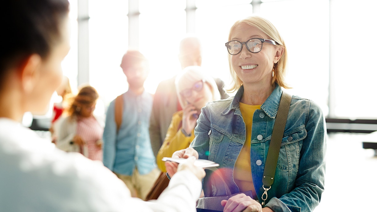 Woman exchanging documents at a ticket counter in a travel marketplace.