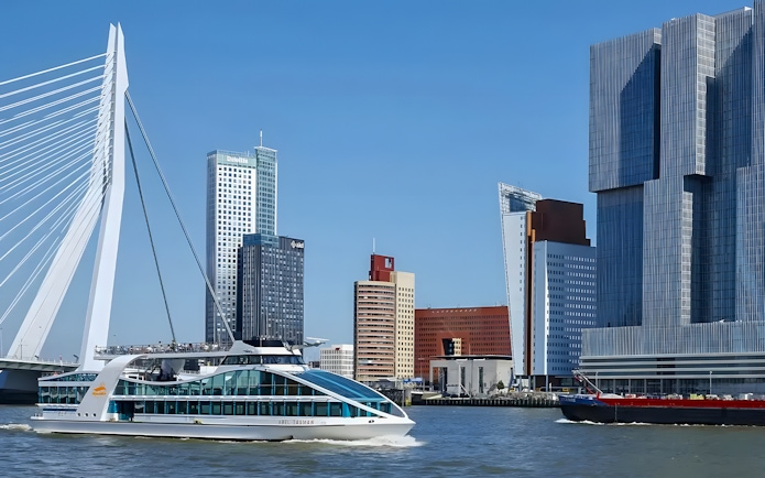 Cruise ship passing Erasmus Bridge and modern skyline in Rotterdam Harbor.