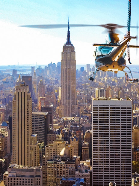 Helicopter flying over New York City skyline with Empire State Building in view.