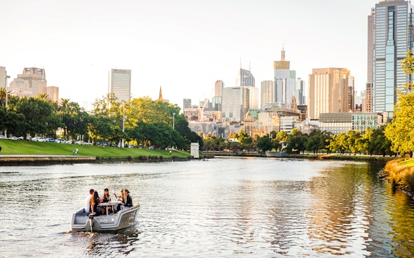 Group enjoying a self-drive picnic cruise on Yarra River with Melbourne skyline in background.