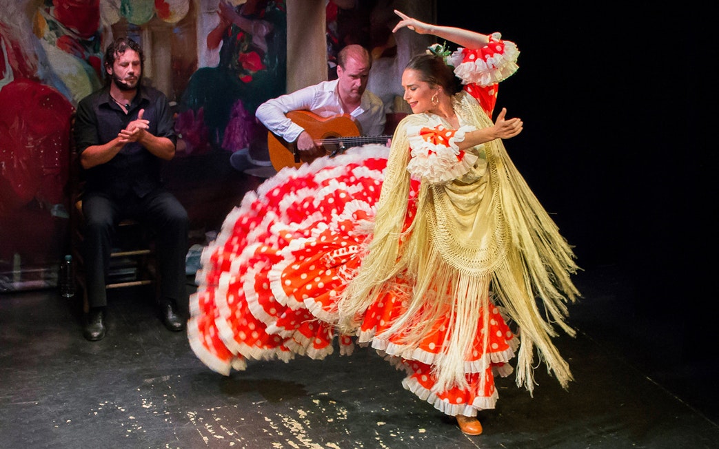 Flamenco dancer performing at Teatro Flamenco Triana with guitarist and singer.