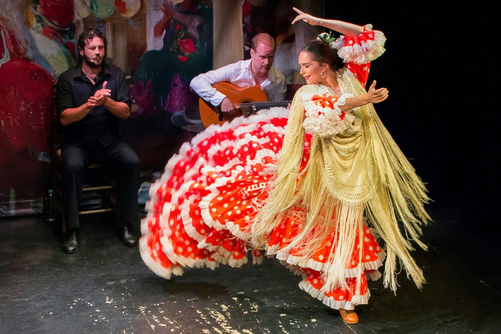 Flamenco dancer performing at Teatro Flamenco Triana with guitarist and singer.