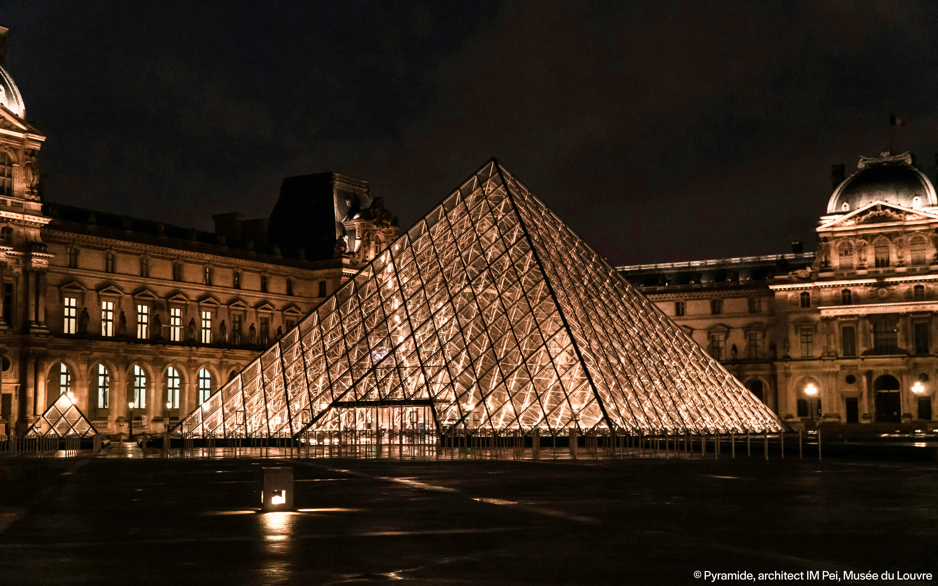 Louvre Pyramid illuminated at night in Paris, France.