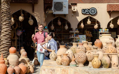 Tourists exploring pottery market in Nizwa, Oman, with traditional clay pots on display.