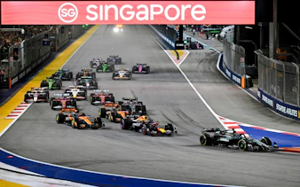 Formula 1 cars racing at night during the Singapore Grand Prix.