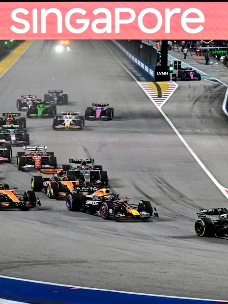 Formula 1 cars racing at night during the Singapore Grand Prix.