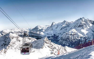 Cable car ascending to Schilthorn Piz Gloria with snowy Swiss Alps in the background.