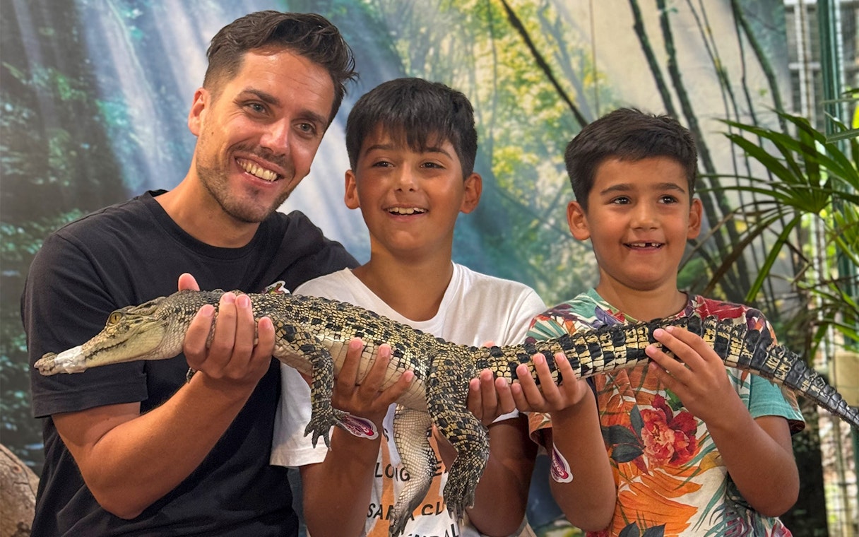 Visitors holding a young crocodile at Crocodile Adventureland Langkawi.