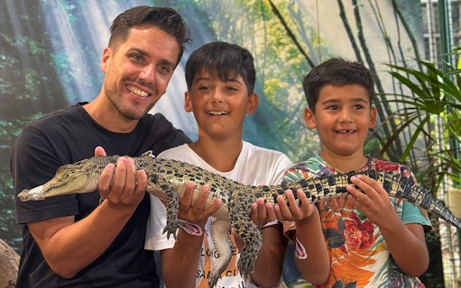 Visitors holding a young crocodile at Crocodile Adventureland Langkawi.