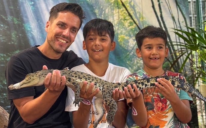 Visitors holding a young crocodile at Crocodile Adventureland Langkawi.