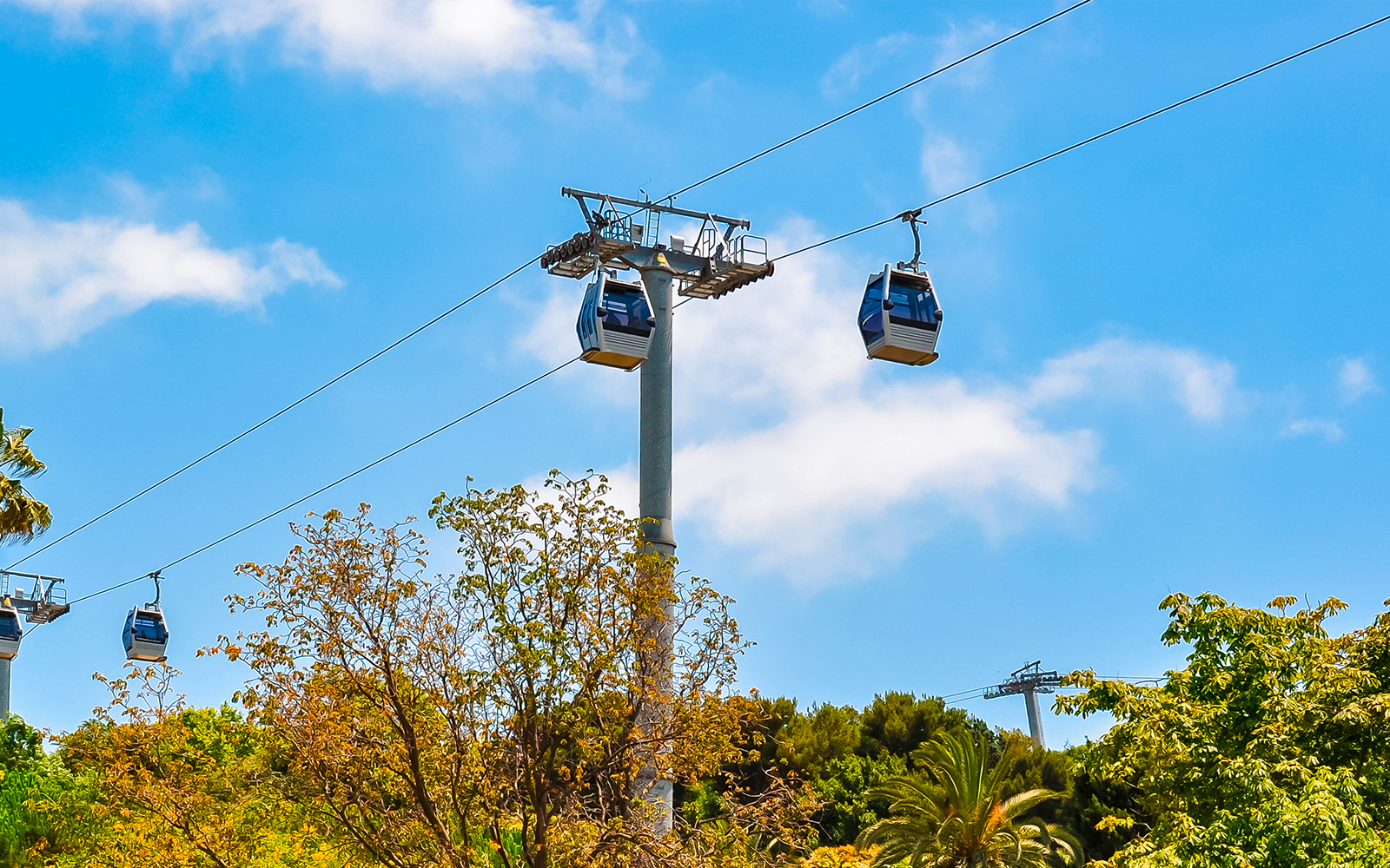 Cable cars ascending Montjuic hill in Barcelona, Spain, with trees below.