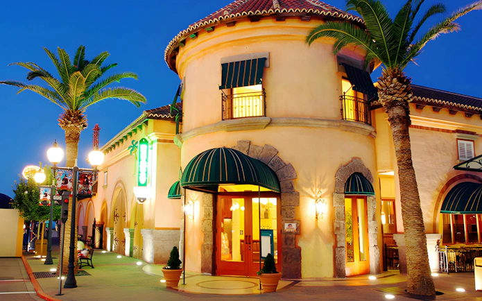Parque Warner entrance illuminated at night with palm trees and street lamps.