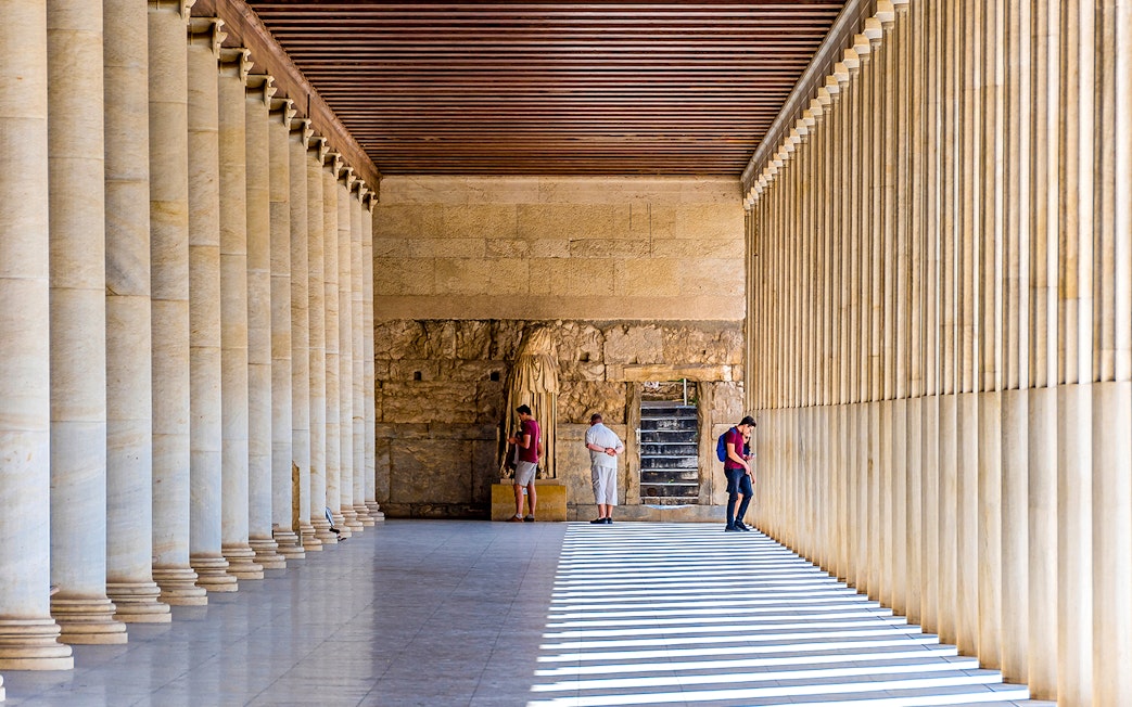 Ancient Agora of Athens colonnade with visitors exploring historic site.