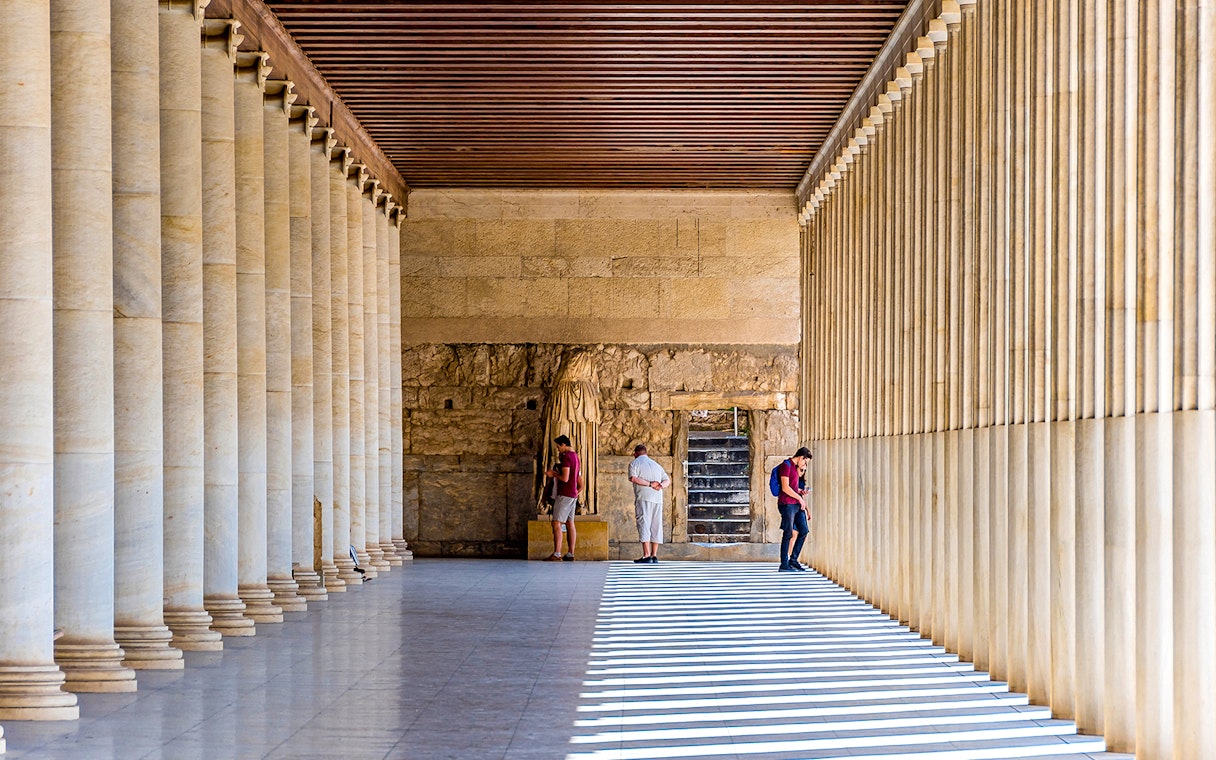 Ancient Agora of Athens colonnade with visitors exploring historic site.