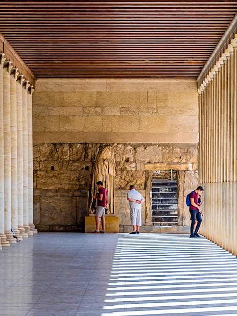 Ancient Agora of Athens colonnade with visitors exploring historic site.