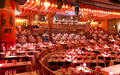Dining setup at Moulin Rouge Show in Paris with red lamps and tiered seating.