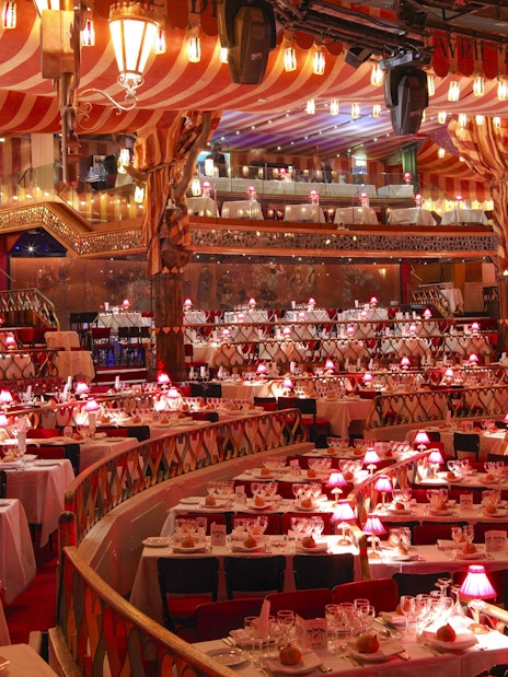 Dining setup at Moulin Rouge Show in Paris with red lamps and tiered seating.