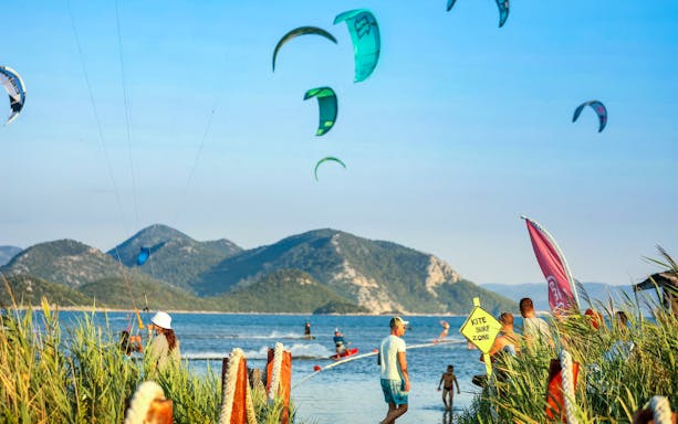 Kiteboarders at Delta Neretva, Croatia with mountains in the background.