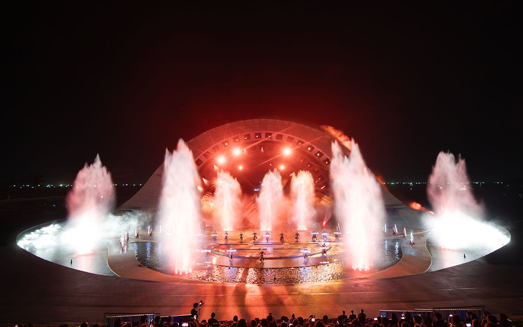 Fountain and light display at Kiss of the Sea Show, featuring performers on stage.