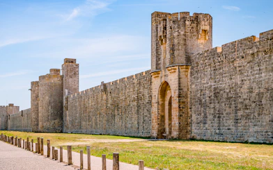 Towers and ramparts of Aigues-Mortes under a clear blue sky.