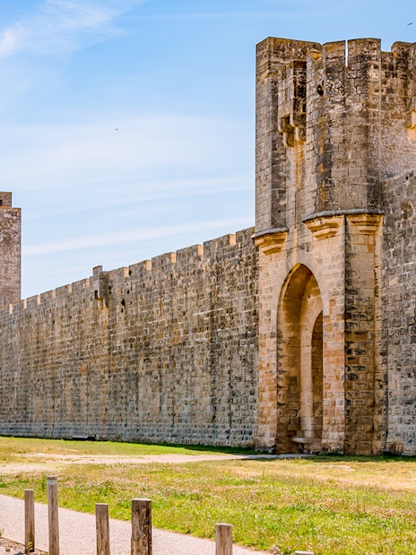 Towers and ramparts of Aigues-Mortes under a clear blue sky.