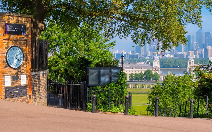 Royal Observatory Greenwich entrance with view of London skyline and historic buildings.
