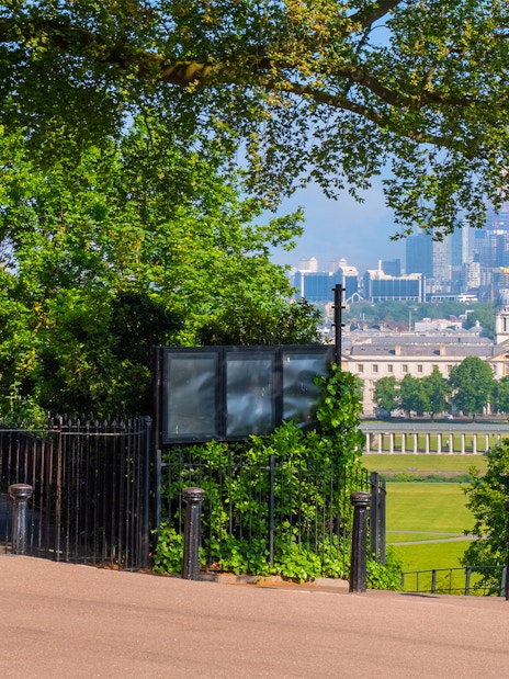 Royal Observatory Greenwich entrance with view of London skyline and historic buildings.