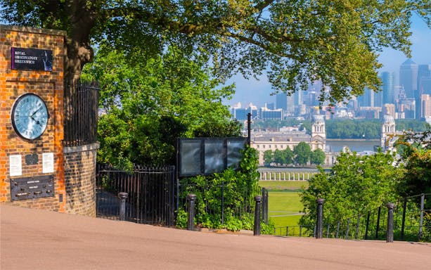 Royal Observatory Greenwich entrance with view of London skyline and historic buildings.