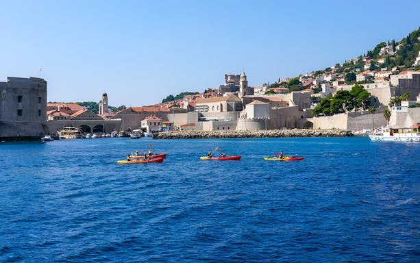 Kayakers on the Adriatic Sea near Dubrovnik's historic city walls, en route to Betina Cave Beach.