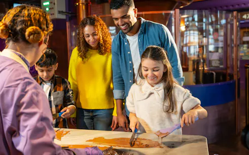 Family enjoying chocolate-making activity at Cadbury World.