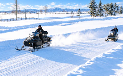 Snowmobiling in Sapporo's snowy landscape during Otaru, Snow Park & Shiroi Koibito Park Day Tour, Hokkaido.