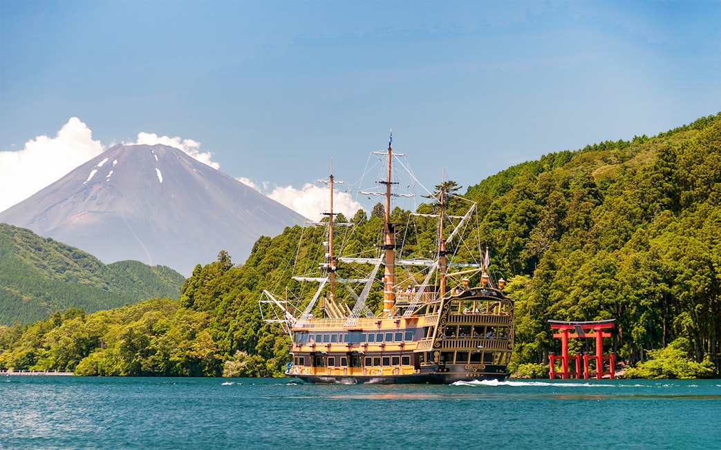 Sightseeing cruise ship on Lake Ashi with Mount Fuji and torii gate in Kamakura.