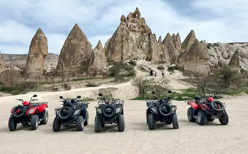ATVs parked in front of Cappadocia rock formations, Turkey, ready for a tour.