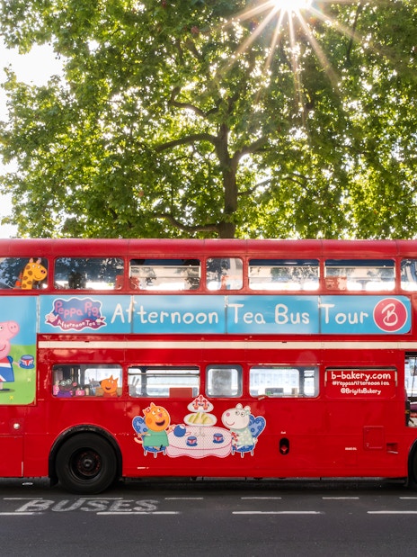 Red double-decker bus for Brigit’s Afternoon Tea Tour in London with London Eye in background.