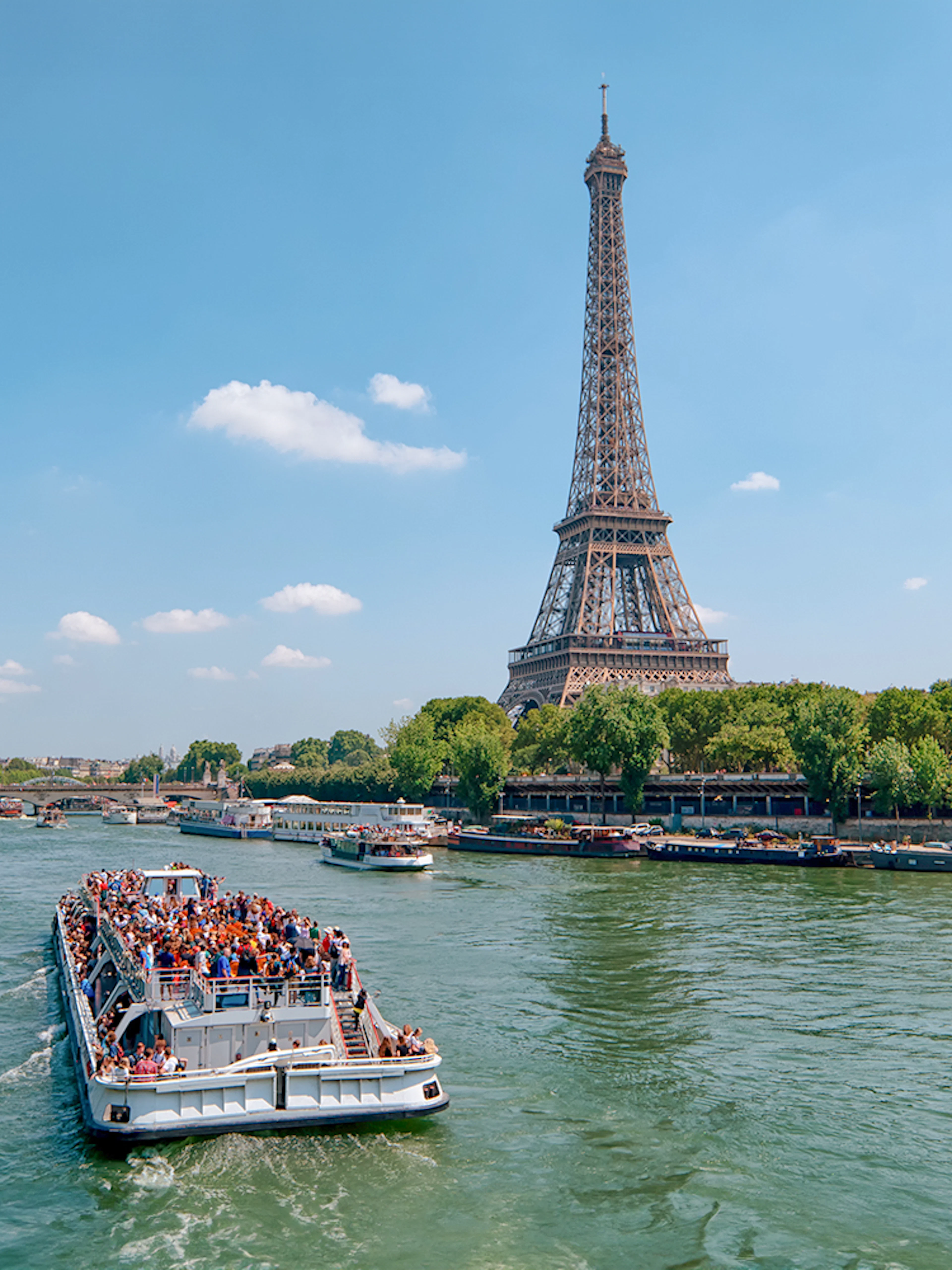 Seine River cruise boat near Eiffel Tower, Paris, during morning tour.