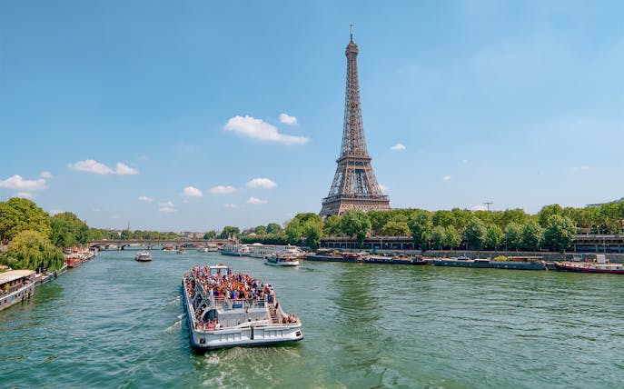 Seine River cruise boat near Eiffel Tower, Paris, during morning tour.