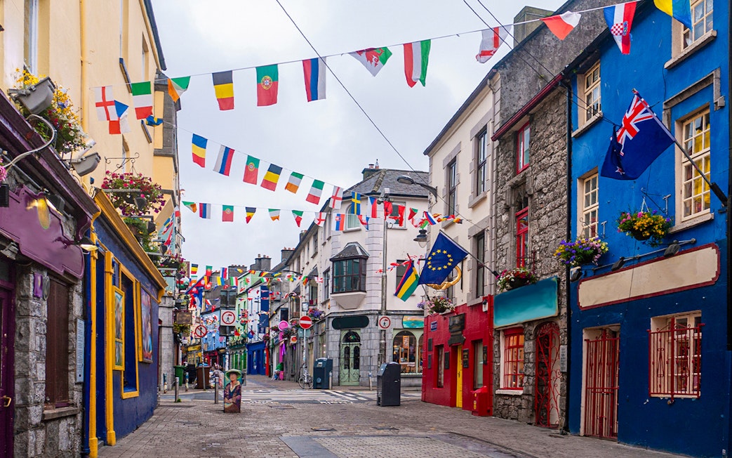 Colorful buildings and international flags on the main high street in Galway City.