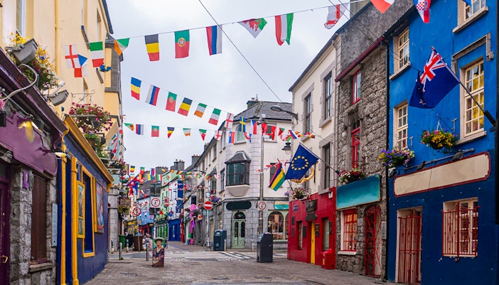 Colorful buildings and international flags on the main high street in Galway City.