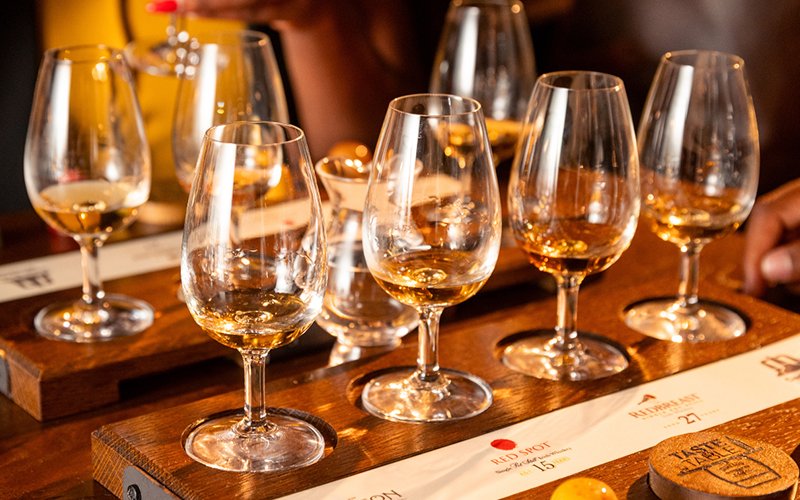 Jameson whiskey tasting glasses with chocolate pairing on a wooden tray.