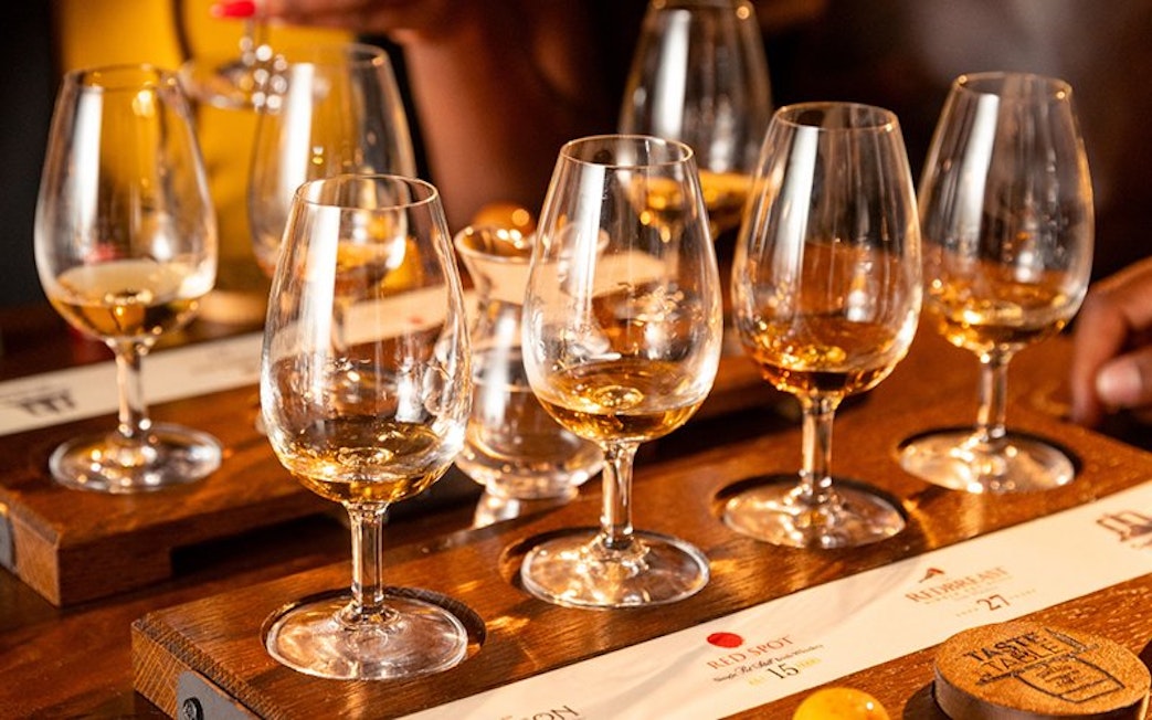 Jameson whiskey tasting glasses with chocolate pairing on a wooden tray.