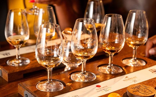 Jameson whiskey tasting glasses with chocolate pairing on a wooden tray.