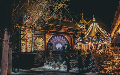 Tivoli Gardens at night with illuminated carousel and ornate building in Copenhagen.