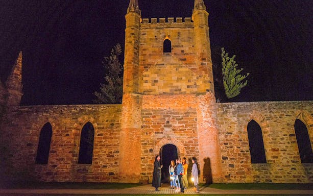 Group on Port Arthur Historic Site Ghost Tour at night, standing by historic ruins.