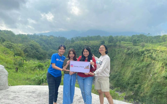 Group of people holding a sign with lush greenery and hills in the background, Dubai Lava Tour.