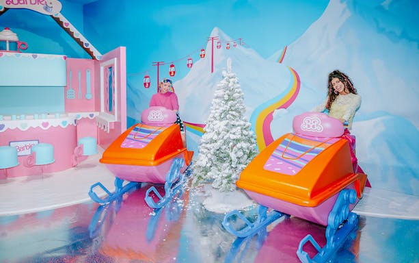 Barbie-themed ski ride with colorful sleds and snowy mountain backdrop.