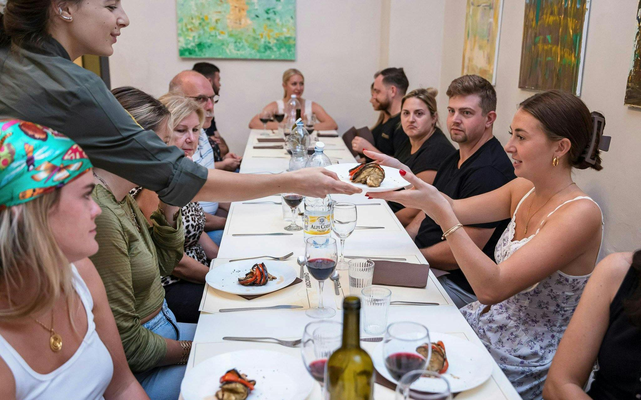 Small group enjoying a cooking class in Florence, sharing dishes at a long table.