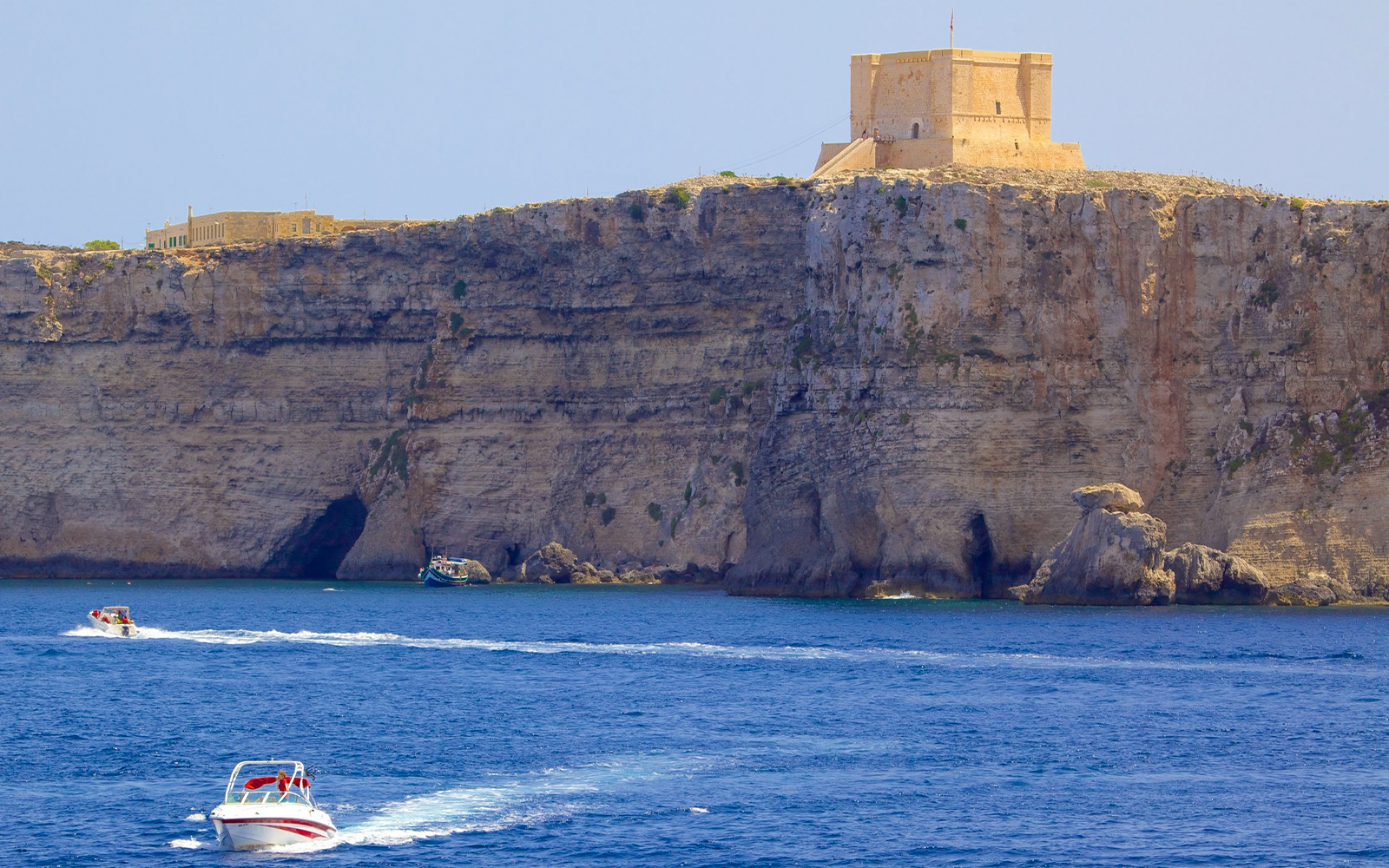 St. Mary's Tower on Comino Island with boats in the foreground.