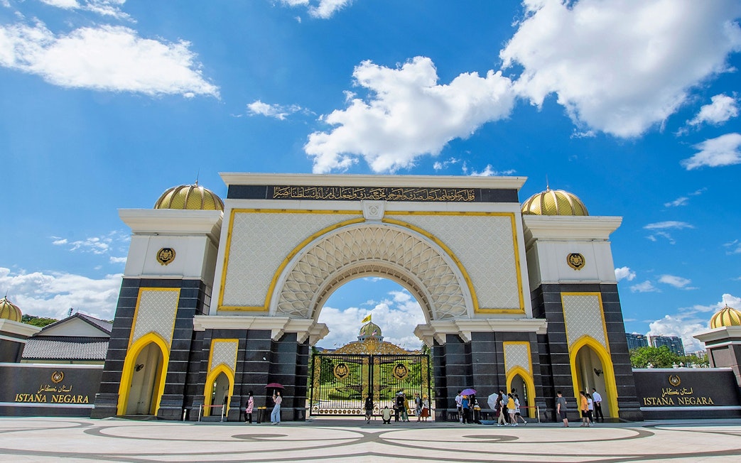Istana Negara entrance in Kuala Lumpur with visitors and blue sky.